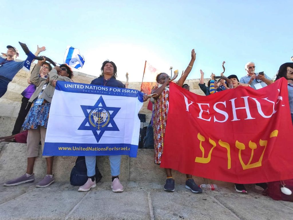Israel tour participants holding UNIFY and Yeshua flags